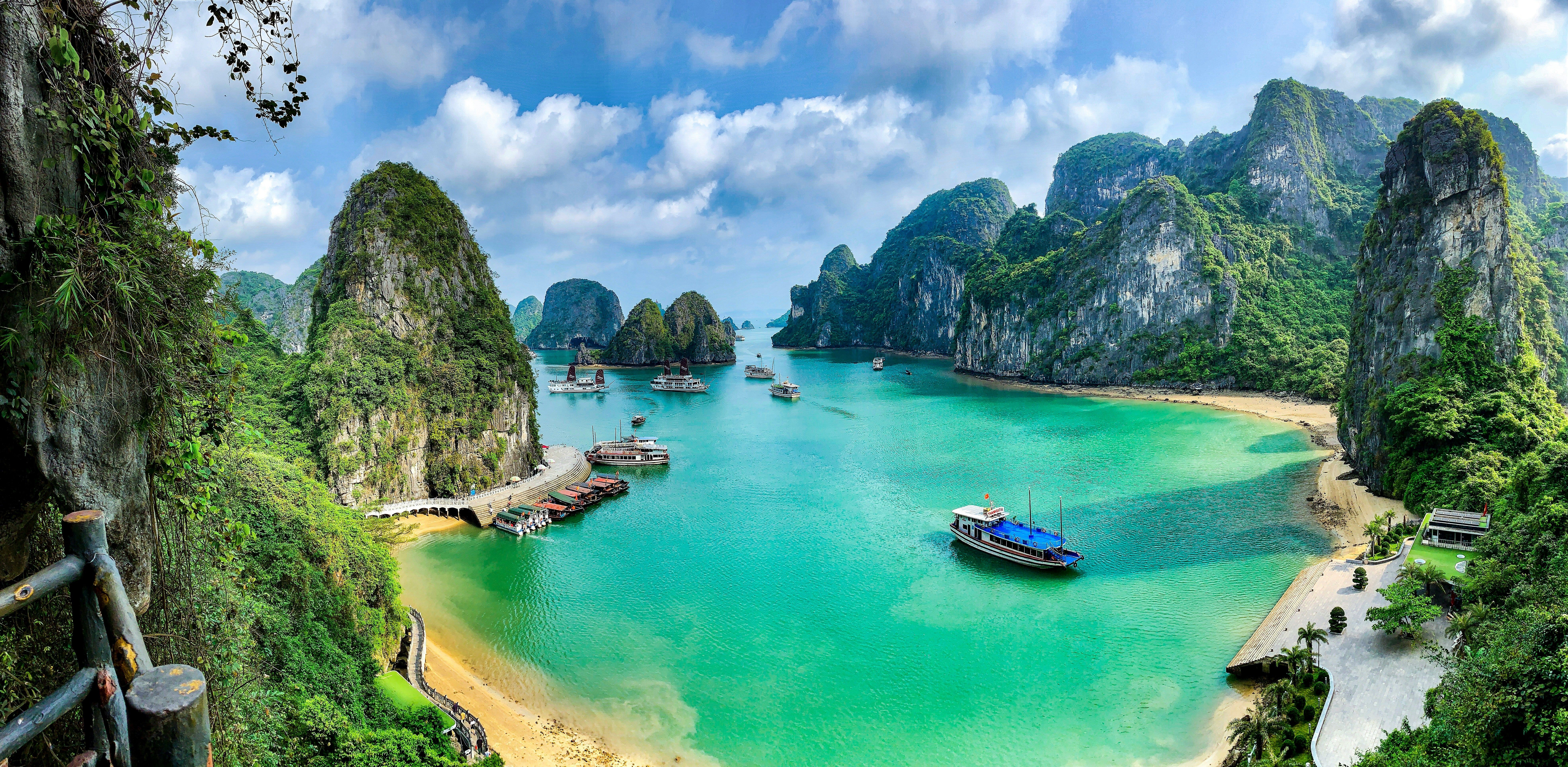Halong Bay Vietnam with turquoise waters, limestone cliffs, sandy beaches, and boats for a scenic cruise in vietnam trip package